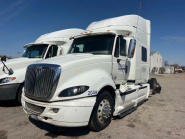 Two white semi-trucks parked side by side.