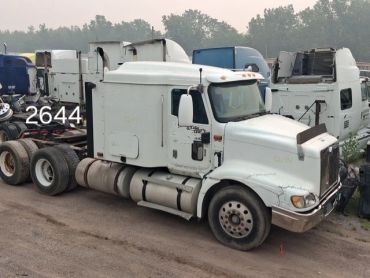 White semi-truck parked in a lot with other trucks.