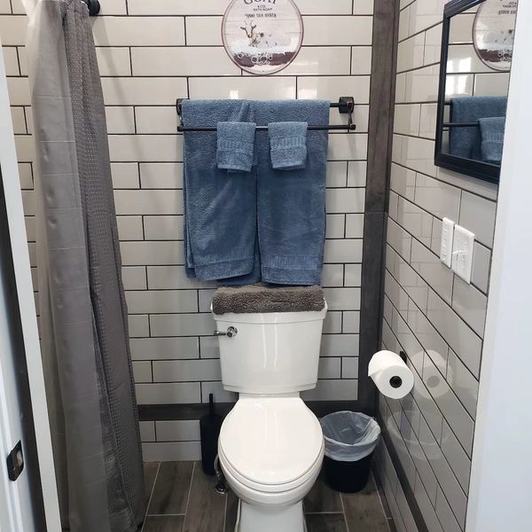 Neat bathroom with white toilet, blue towels, and gray accents.