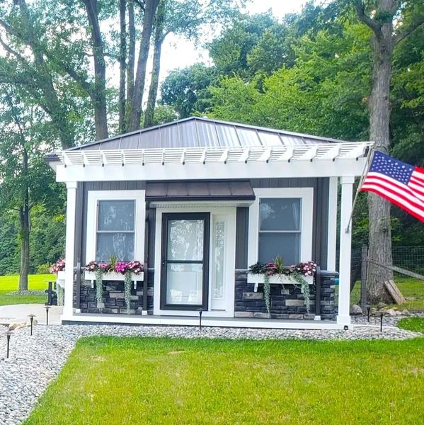 Small modern garden shed with flower boxes and an American flag.