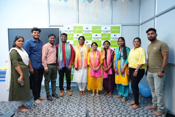 Group of people standing barefoot in front of a congratulatory banner.