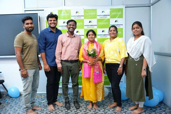 Group of six people standing barefoot in front of a Masters Pharma congratulatory banner.
