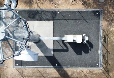 Top-down view of a fenced utility or communication tower base.