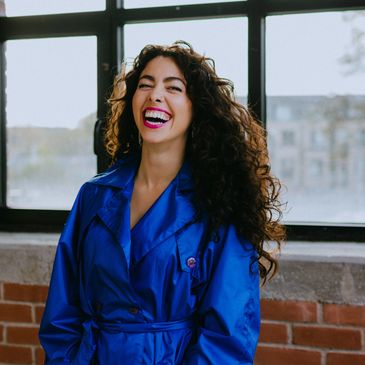 Happy woman with curly hair in a blue coat.
