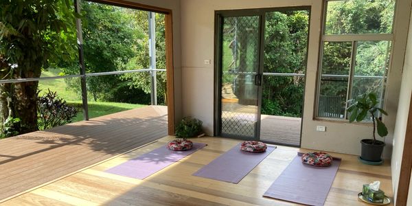 Yoga mats with cushions in a bright, open room overlooking greenery.