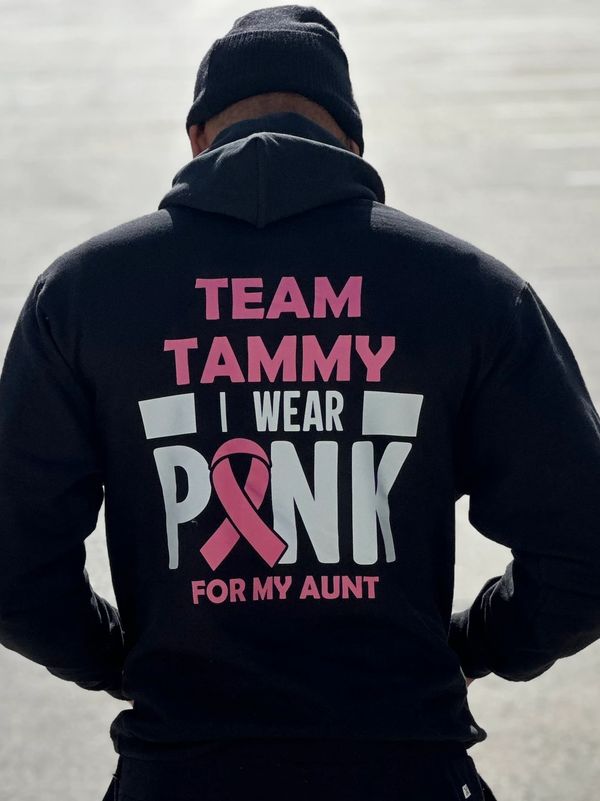 Person wearing a hoodie that says "Team Tammy I Wear Pink For My Aunt" with a pink ribbon.