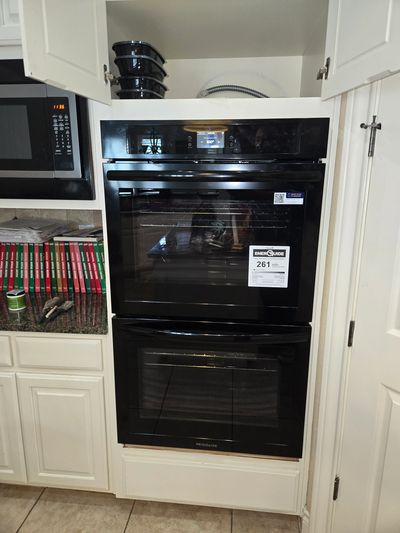 Modern black double oven built into white kitchen cabinetry.