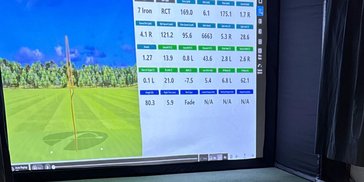 Indoor golf simulator showing detailed radar data and ball trajectory on a large screen.