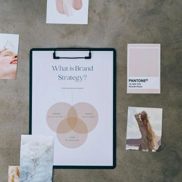Flat lay of brand strategy poster, Pantone swatch, and various photos on a gray surface.