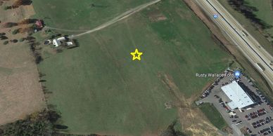 Aerial view of a green field with a yellow star marking a spot.