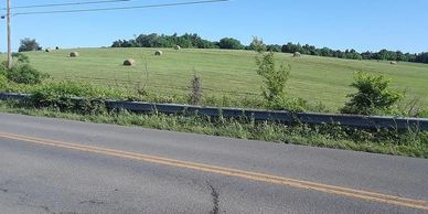 Country road with green fields and hay bales.
