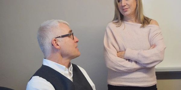 Two colleagues engaged in a serious conversation in an office setting.
