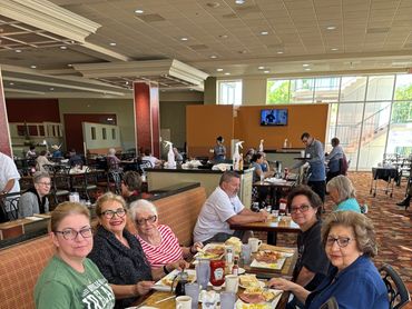 A group of older adults enjoying a meal together in a bright dining area.