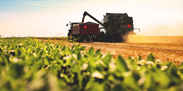 Combine harvester transferring grain to a tractor trailer in a field.