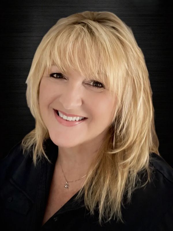 Smiling woman with blonde hair and bangs.
