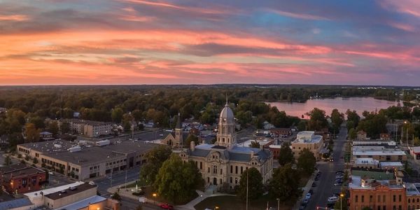 Sunset over a small town with a historic courthouse and a lake in the background.
