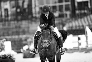 Equestrian rider in helmet applauding horse during event.