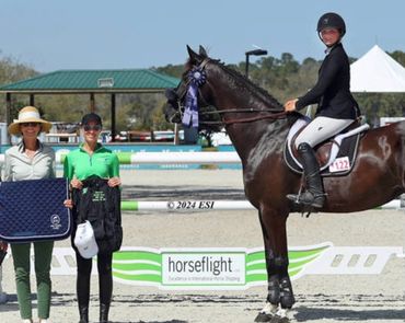 Three women and a rider with a horse at an equestrian event with Horseflight banners.