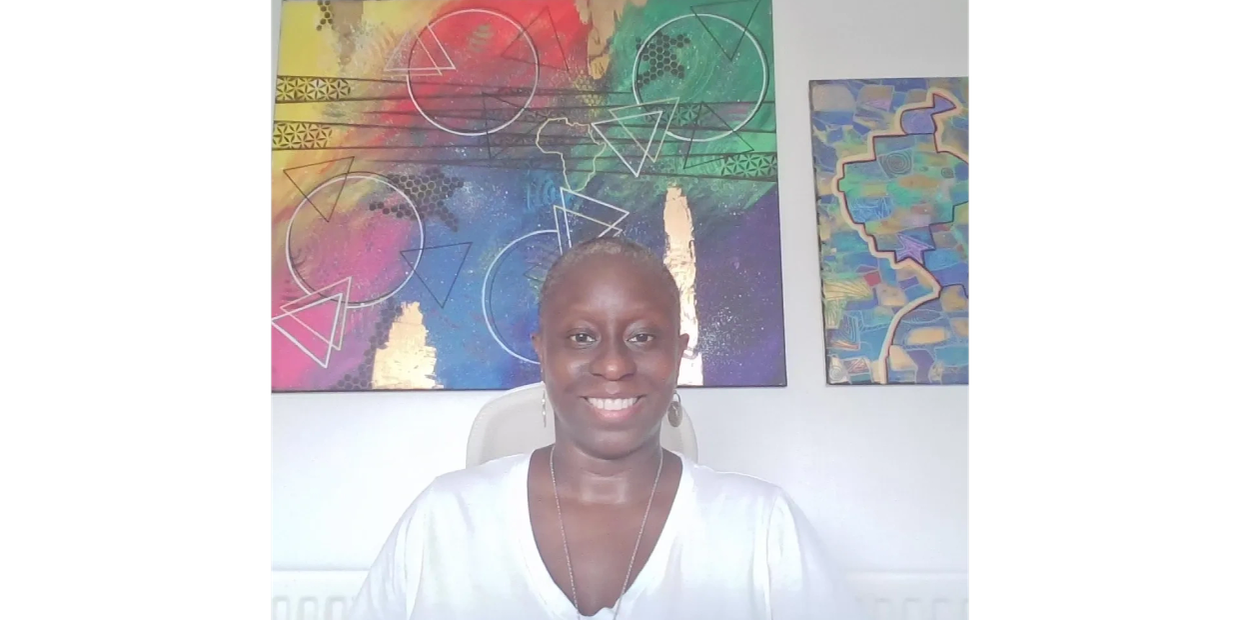 Smiling woman in front of colorful abstract paintings.