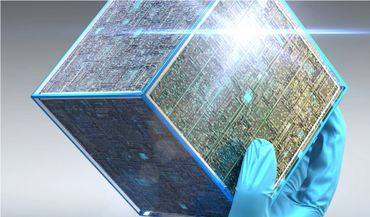 A gloved hand holding a futuristic, glowing cube with intricate circuit patterns.