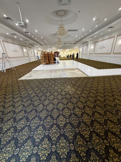Large banquet hall with stacked chairs and chandeliers under renovation.