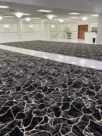 Large empty banquet hall with black patterned carpet and chandeliers.