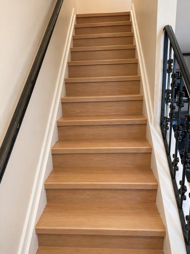 Wooden staircase with black handrails on both sides.