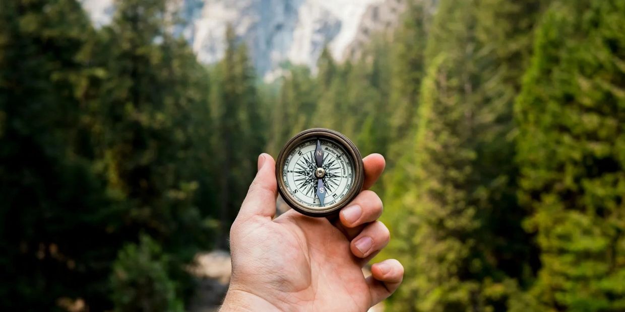 A man holding a compass in the forest