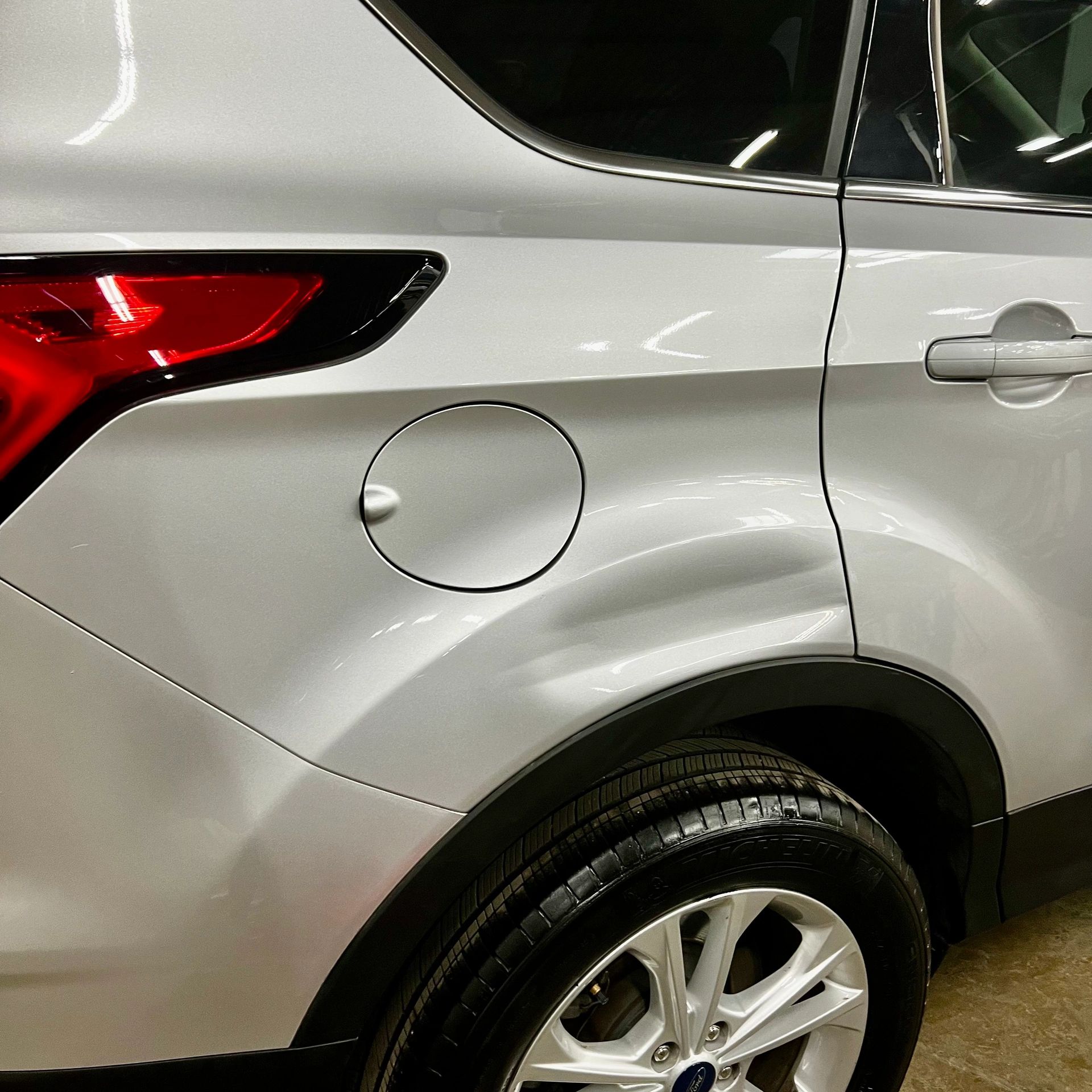 Close-up of a silver Ford SUV's rear side with clean tire and wheel.