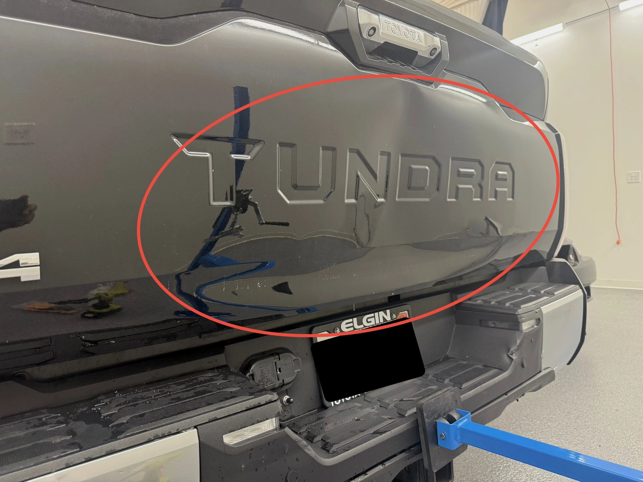Dent on the tailgate of a black Toyota Tundra truck.