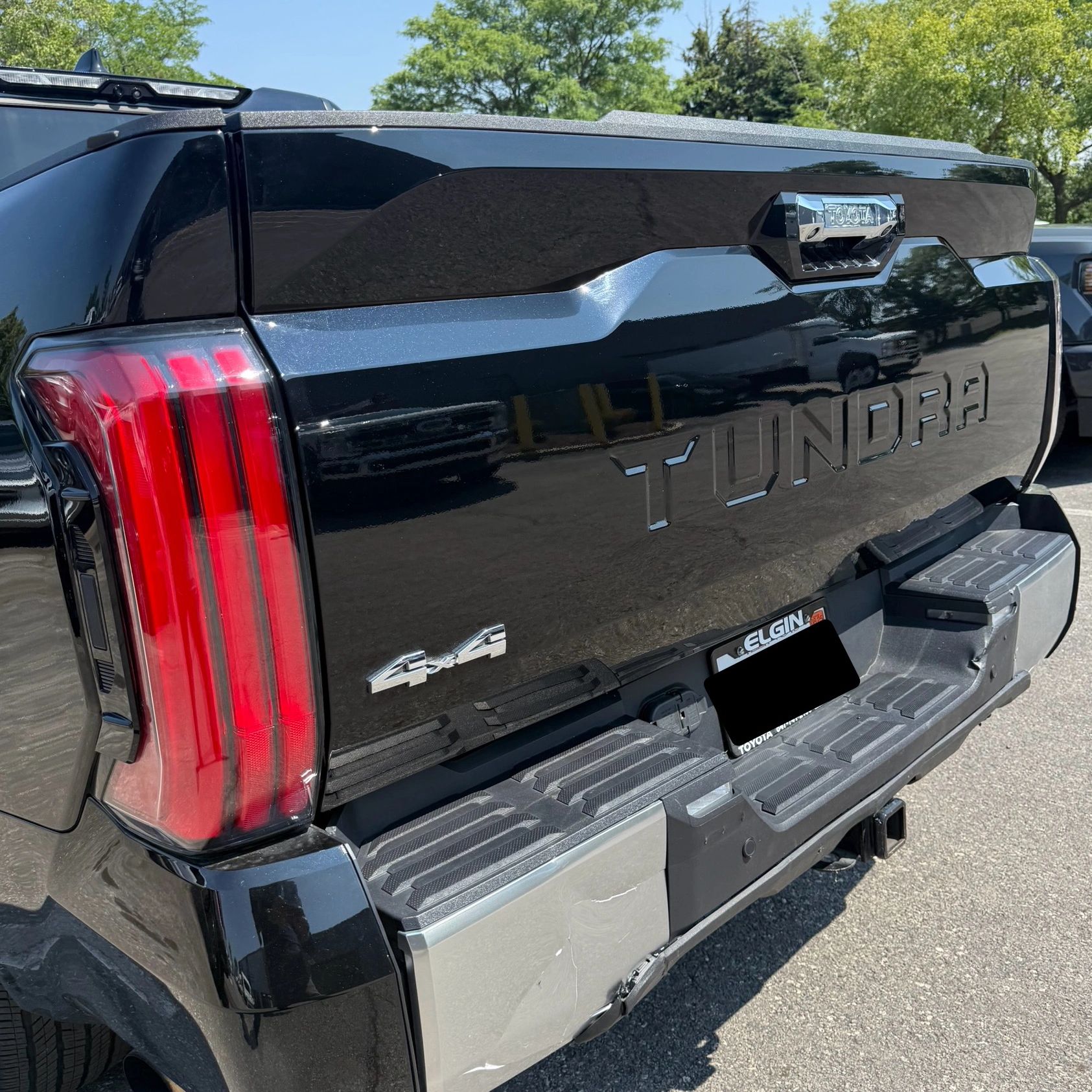 Rear view of a black Toyota Tundra 4x4 truck in a sunny outdoor setting.