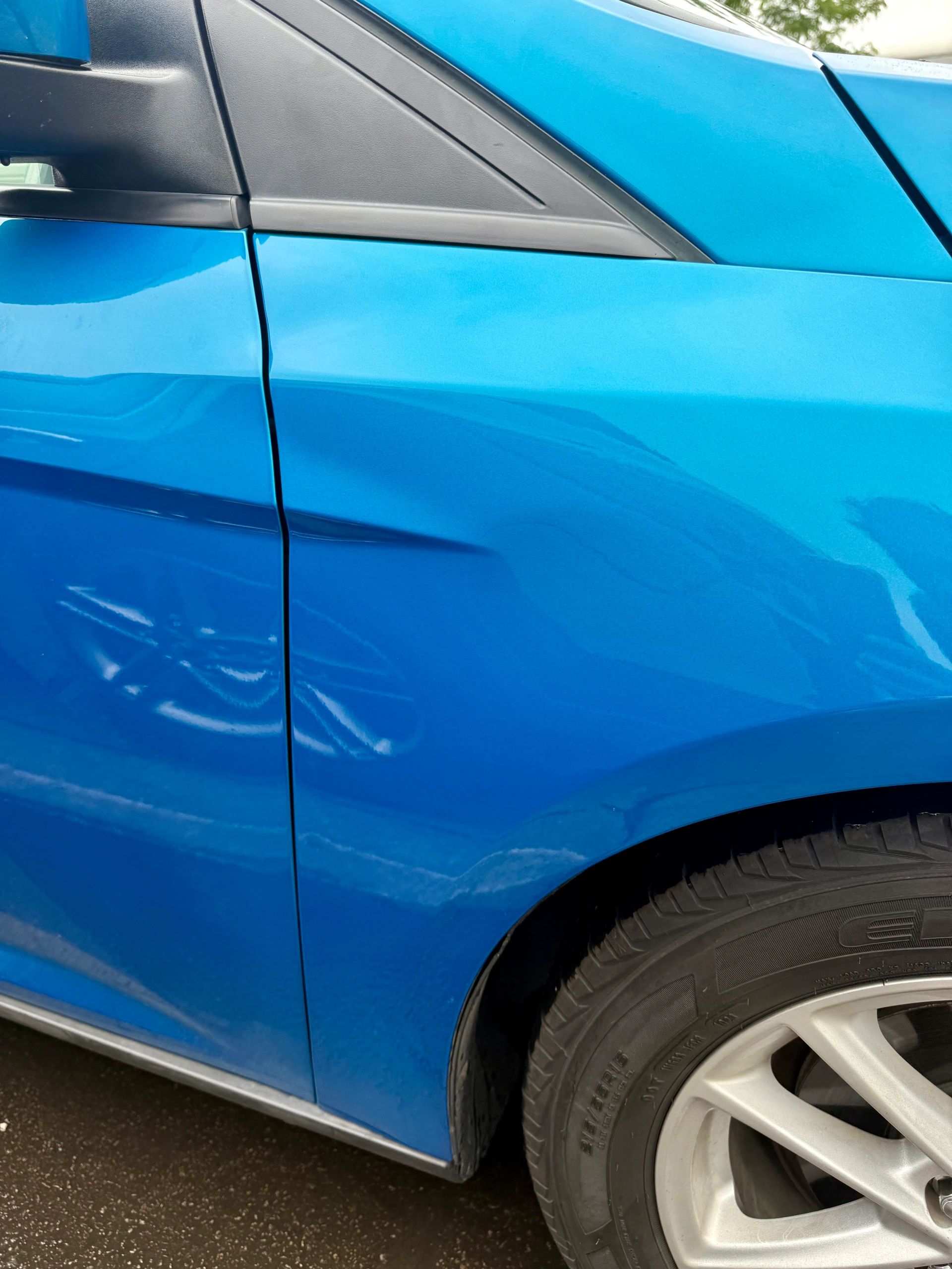 Blue car with a visible dent on the rear door.