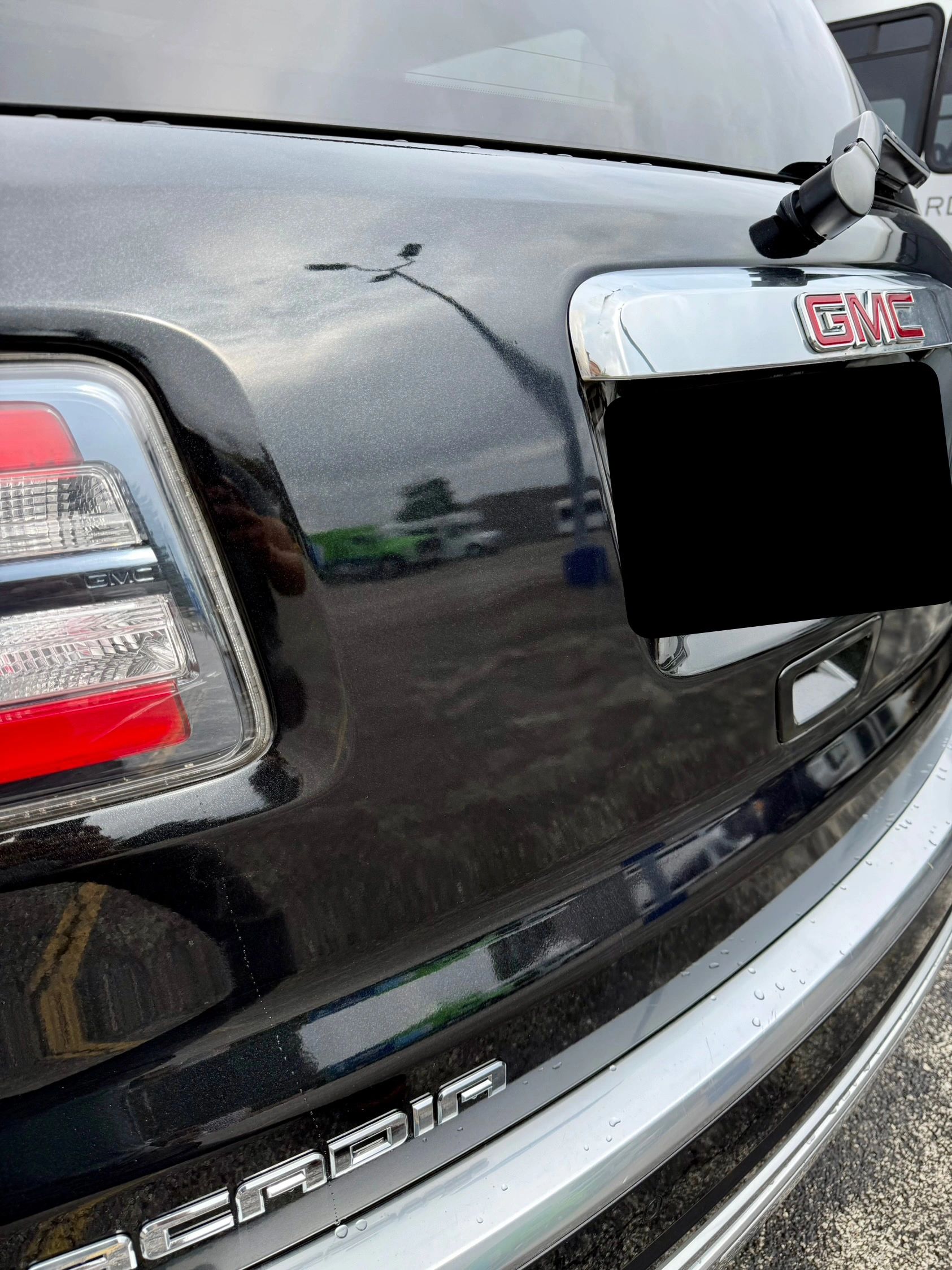 Close-up of the rear of a black GMC Acadia showing the taillight and logo.