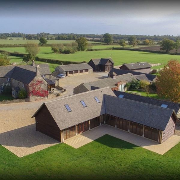 Aerial view of a countryside property with multiple buildings and green fields.