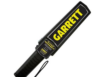 Handheld Garrett metal detector wand with black and yellow design.