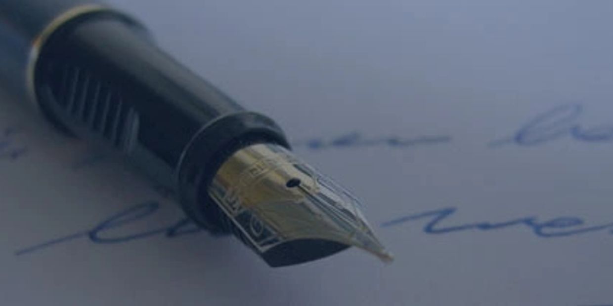 Close-up of a fountain pen nib on handwritten paper.