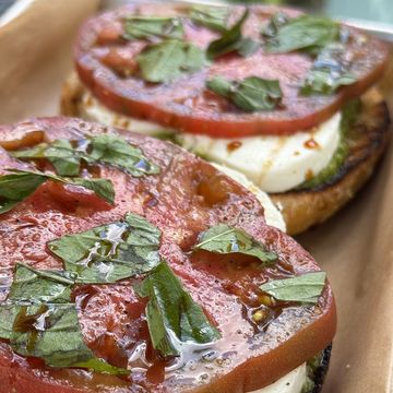 Close-up of fresh tomato and basil on cheese slices.