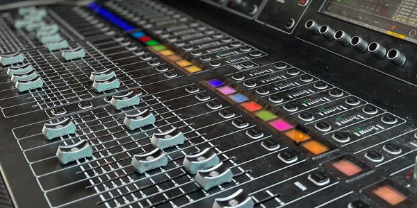 Close-up of a sound mixing console with colorful buttons and sliders.