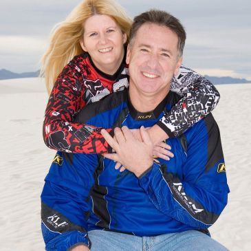 Couple smiling with sandy desert background.