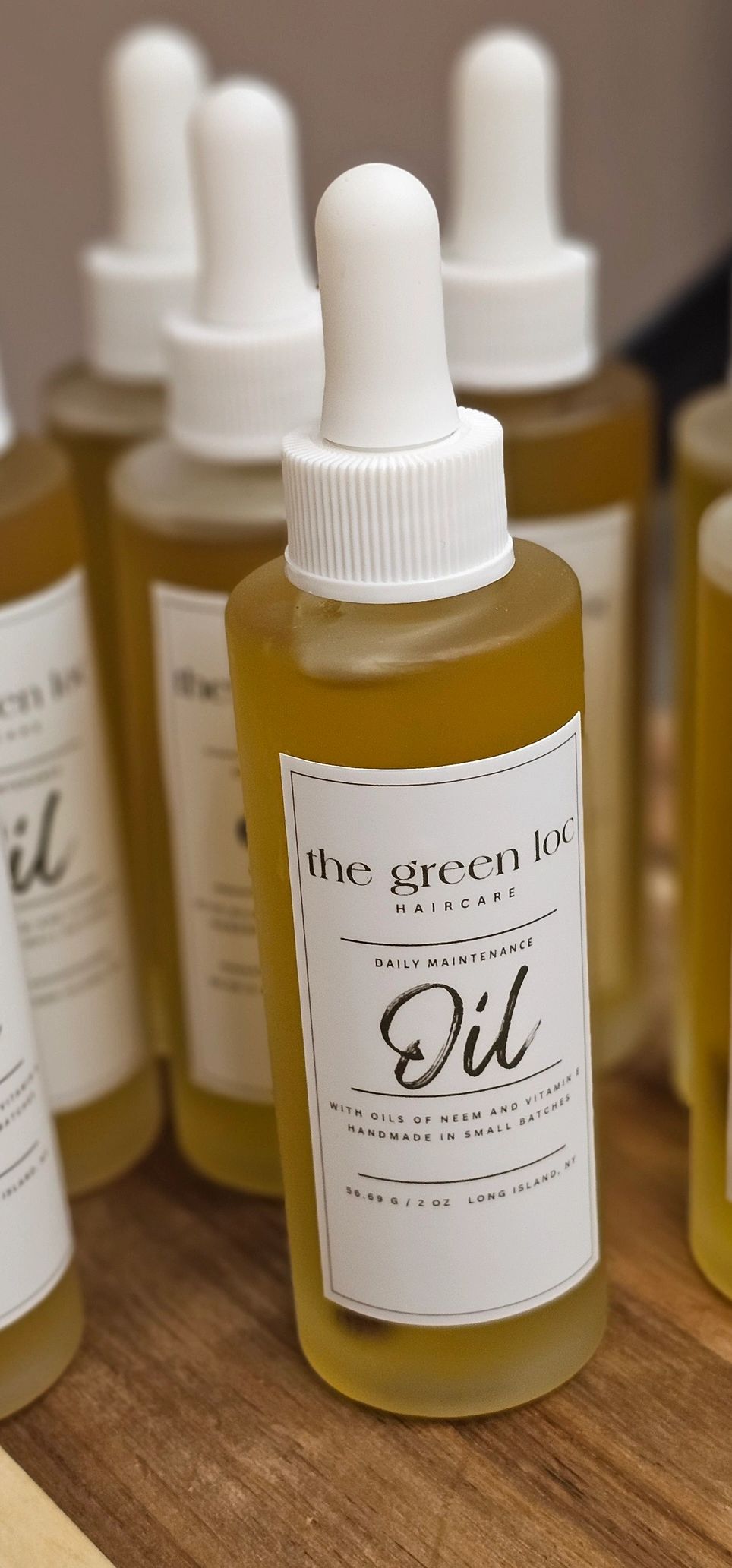 Close-up of haircare oil bottles with white droppers on a wooden surface.