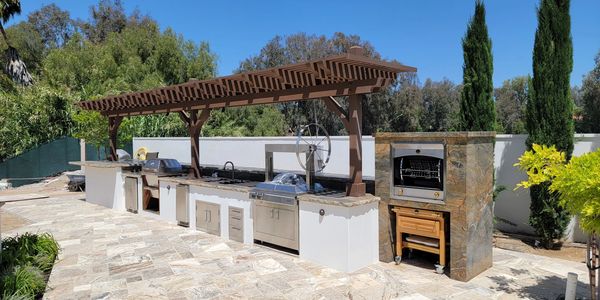Luxury outdoor kitchen with wood pergola and granite countertops