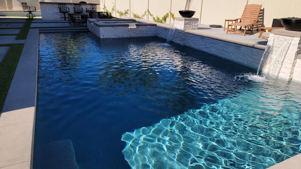 Modern backyard swimming pool in Murrieta California with waterfall features and fire bowls.