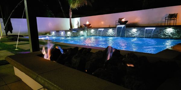 Pool and fire pit at night with laminated water descents and low voltage lighting