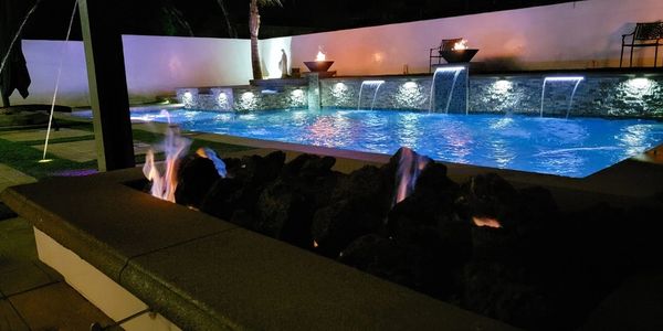 Moreno Valley swimming pool with fire bowls lights at night built by Royal Design Builders
