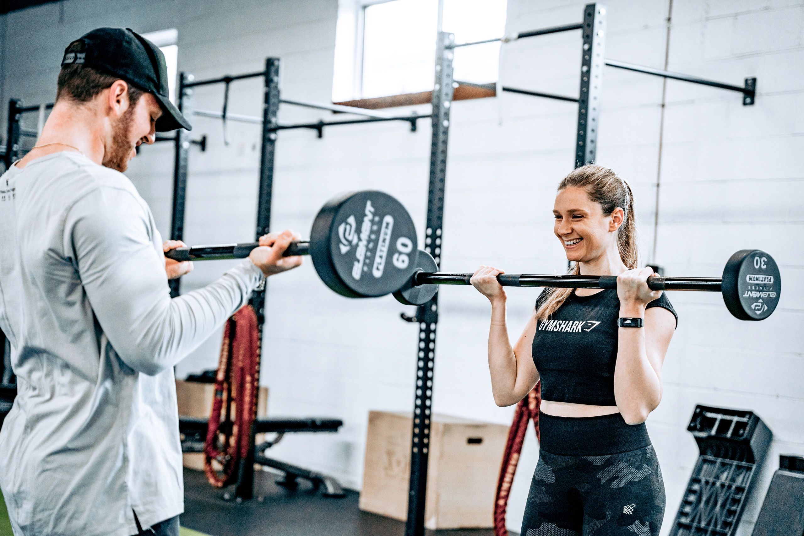 A man spotting a woman lifting weights at the gym.