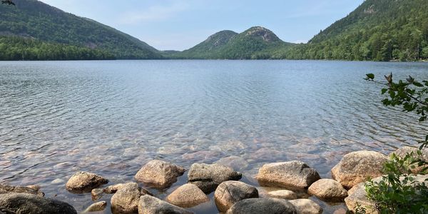 Calm lake with clear water and forested mountains in the background.
