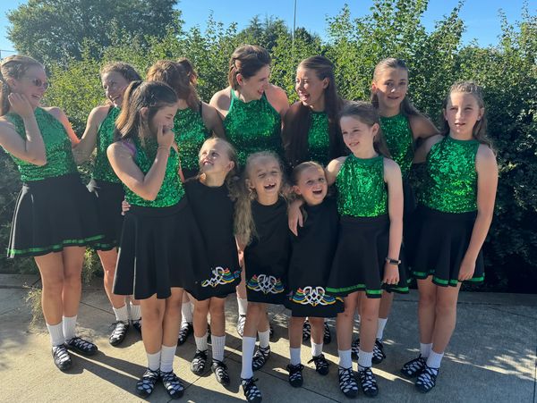 Group of girls in green dance costumes outdoors.