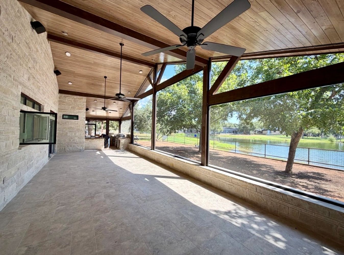 Covered patio with custom motorized shades, wood ceiling, and views of the backyard in Central Texas