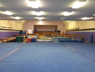 Empty indoor gymnastics training area with mats and equipment.