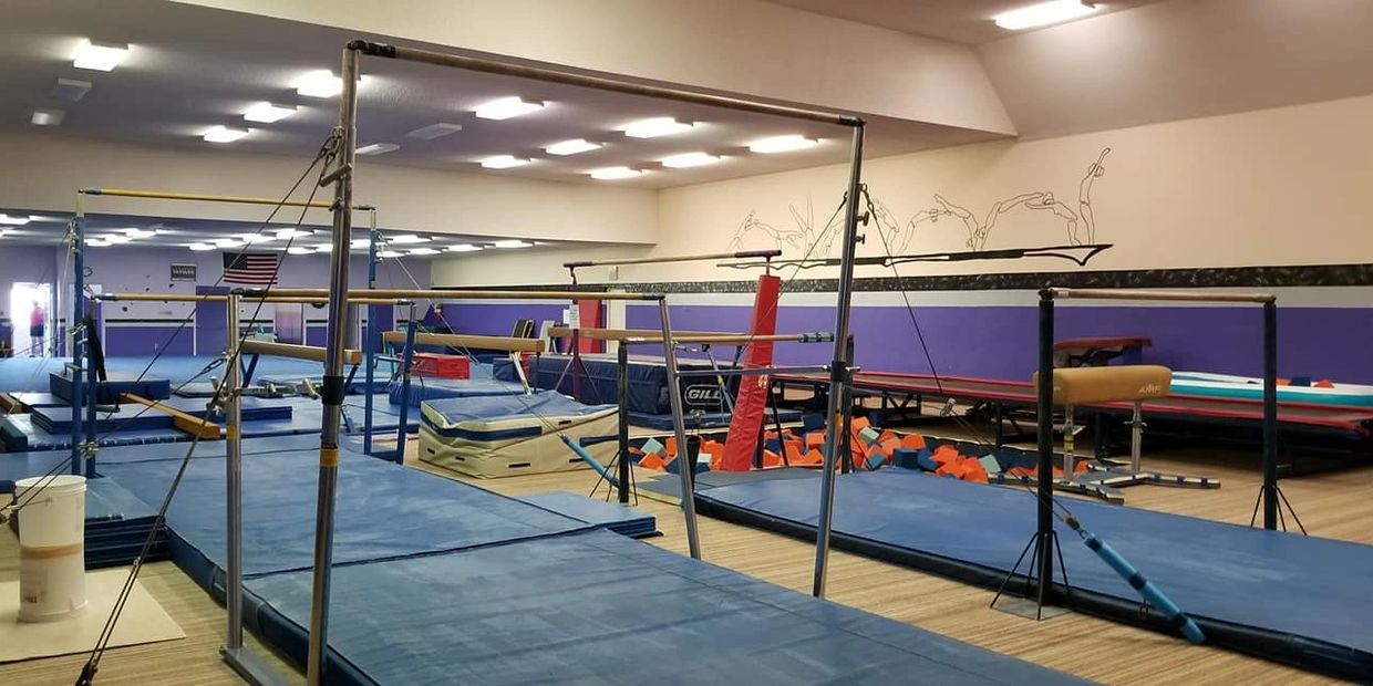 A gymnasium with gymnastics equipment and padded mats.